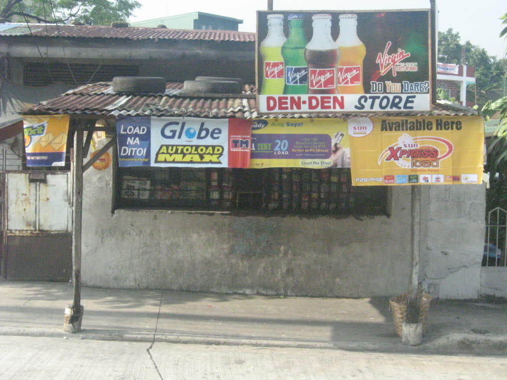 A small neighbourhood sari-sari store with soft-drink and load signs above its window